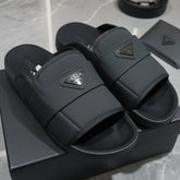 Black slides with Prada logo on a gray surface